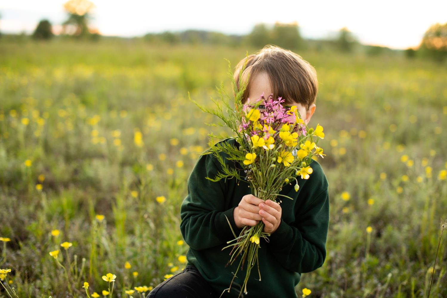 Zu sehen ist: Kind, das sich hinter Blumen versteckt.