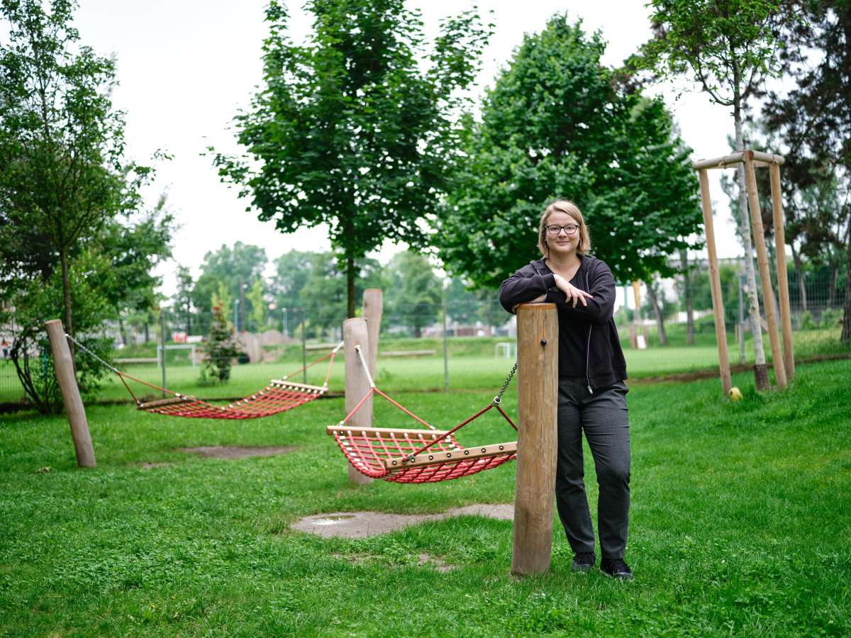 Zu sehen ist. eine Person, die in einem Park an einem Holzpfeiler lehnt.