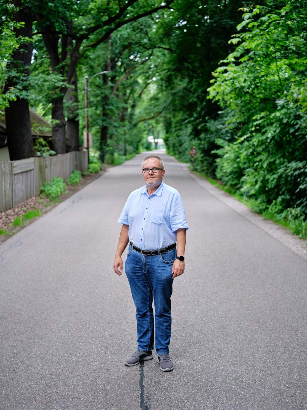 Zu sehen ist: eine Person, die in einer Allee steht.